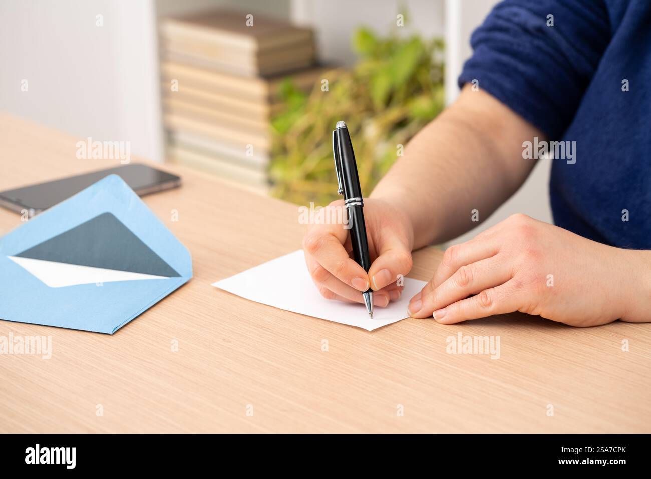 Primo piano di donna mano di scrittura saluto grazie scheda seduto su una scrivania a casa Foto Stock