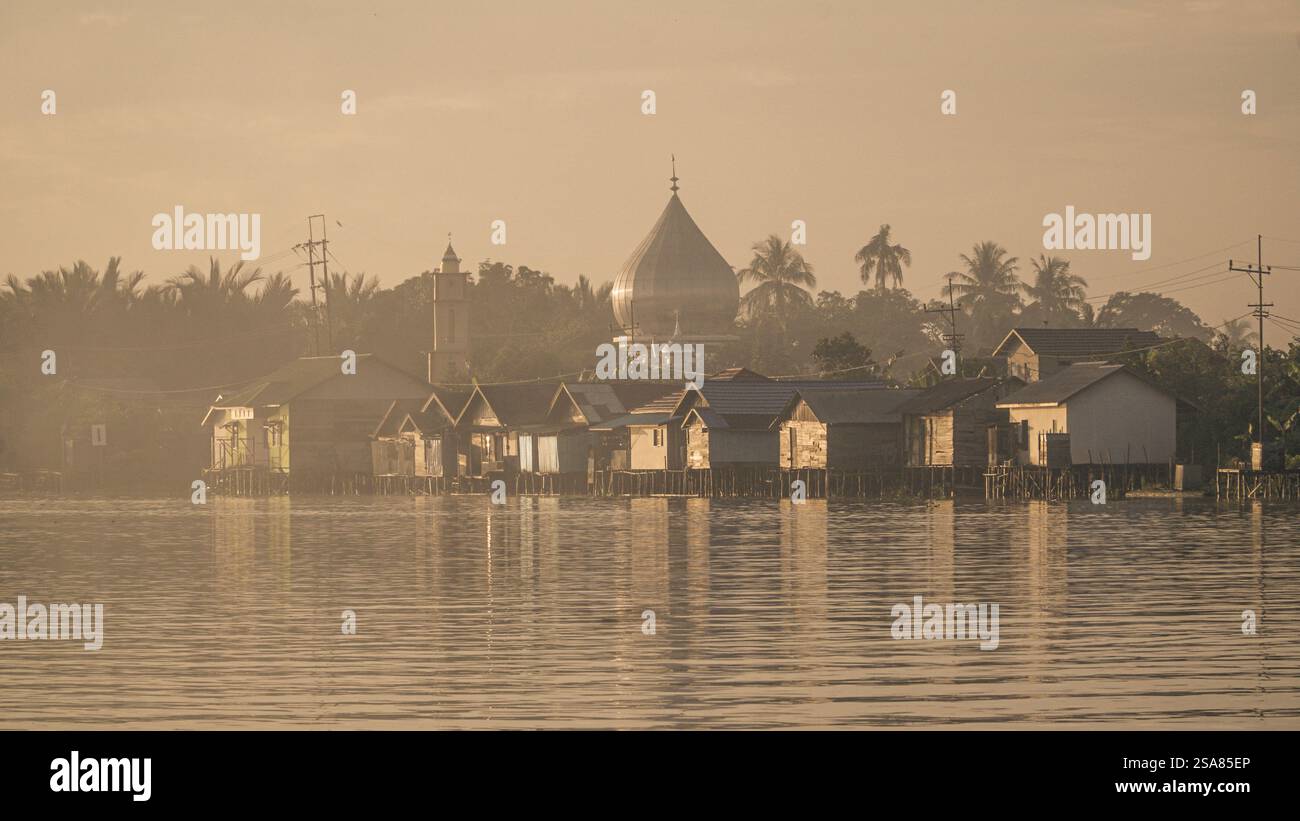 Sereno Villaggio sul lungofiume all'alba con l'importante Moschea Dome e case tradizionali che si riflettono sul fiume Martapura Foto Stock