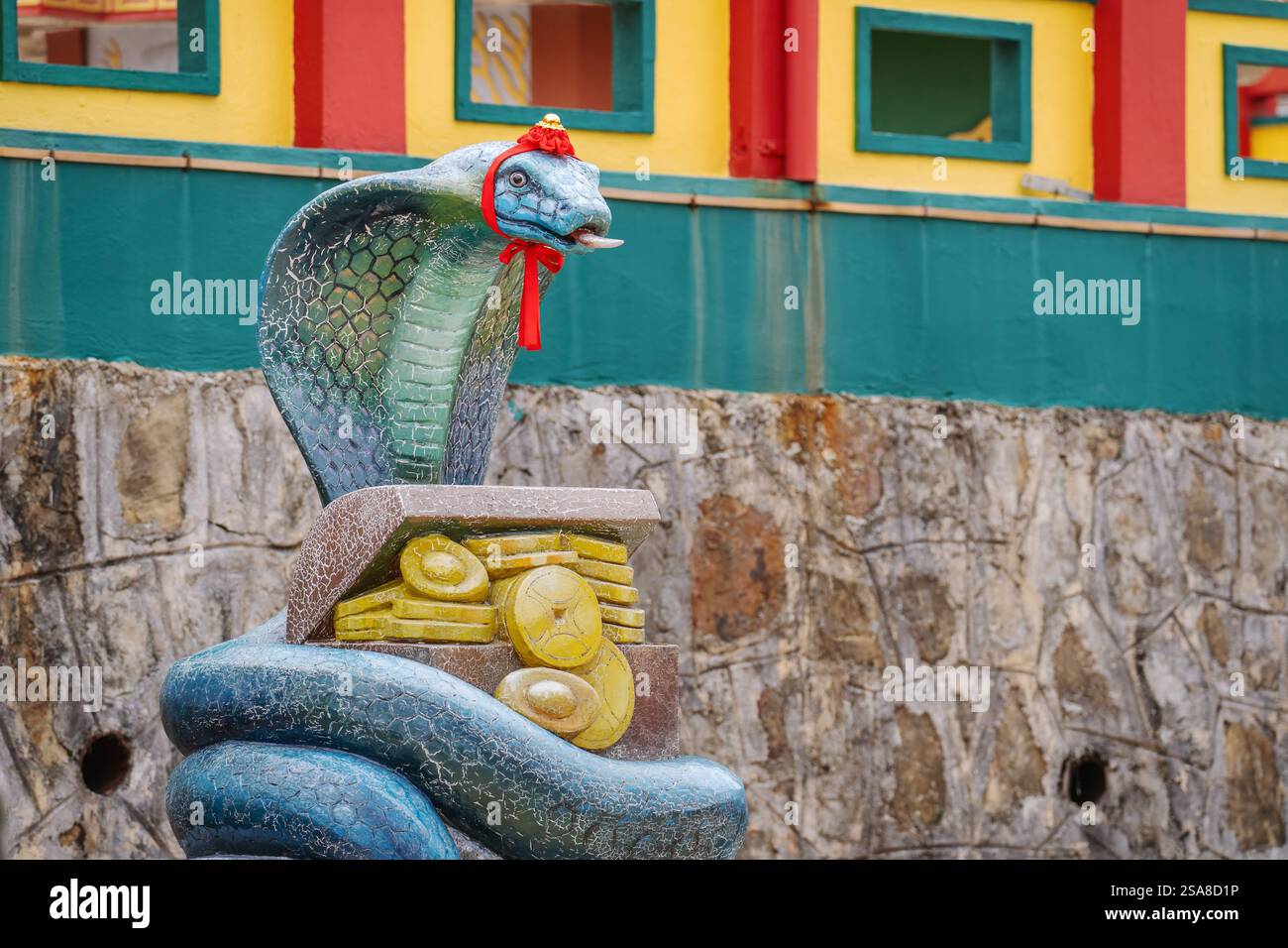 Una statua di serpente blu con un nastro rosso si trova di fronte a una colorata parete del tempio. Tempio Peak Nam Toong a Sabah, Malesia. Foto Stock