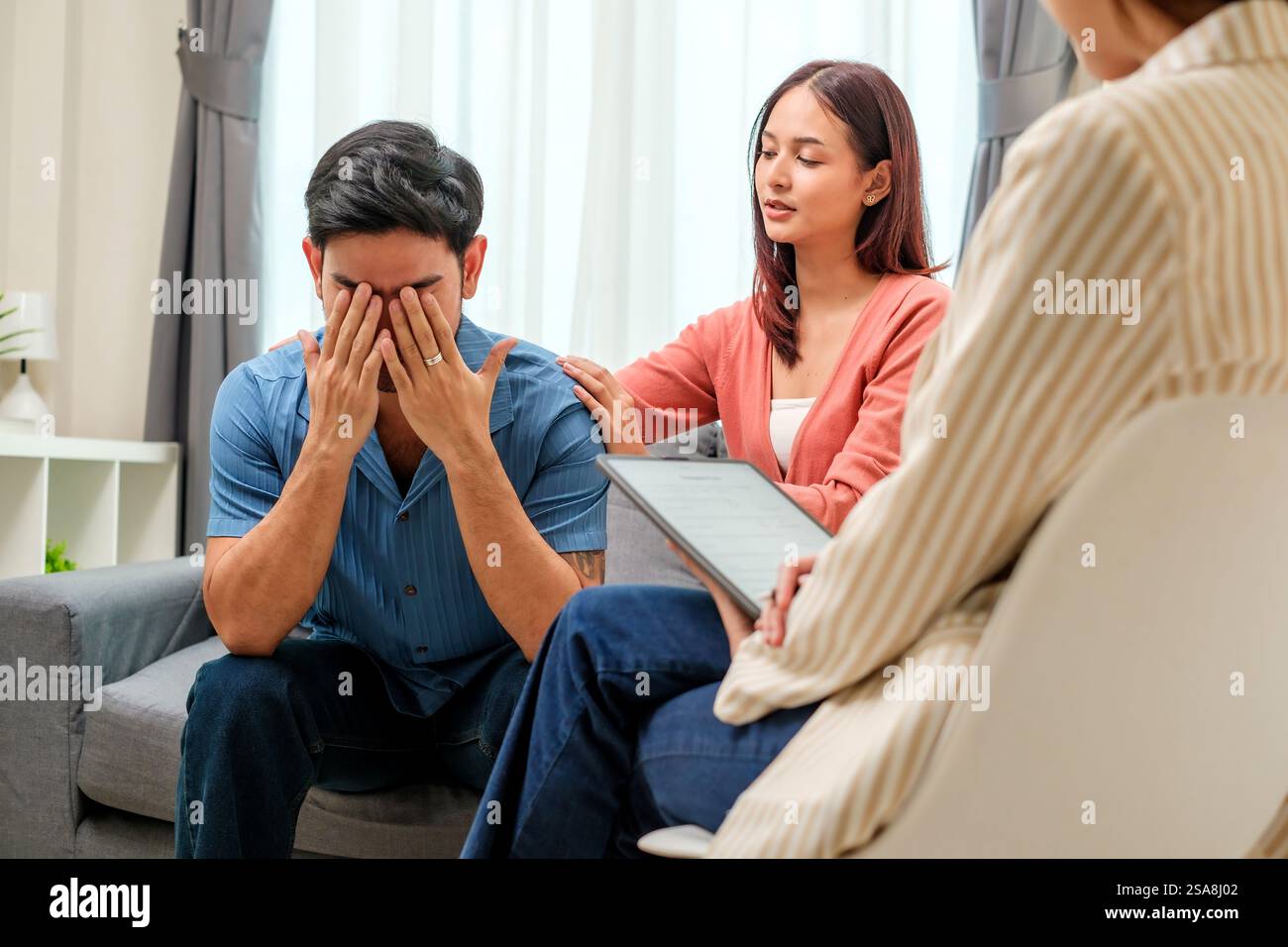 l'uomo in difficoltà si copre il viso con le mani durante una sessione di terapia di coppia Foto Stock
