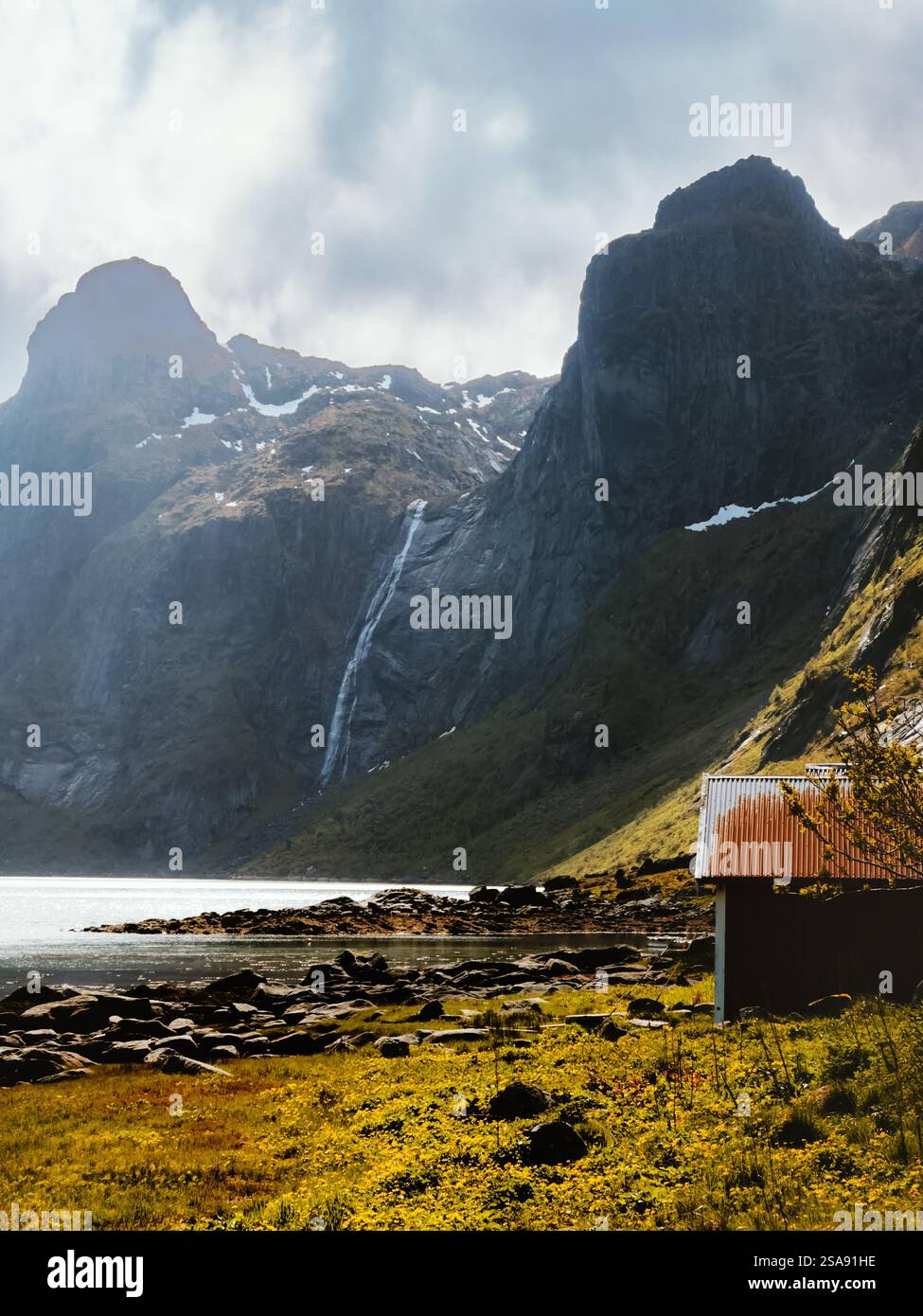 Paesaggio delle isole Lofoten - vecchia casa e vista delle cascate di montagna, viaggia in Norvegia, luogo di riferimento per le splendide destinazioni scandinave Foto Stock