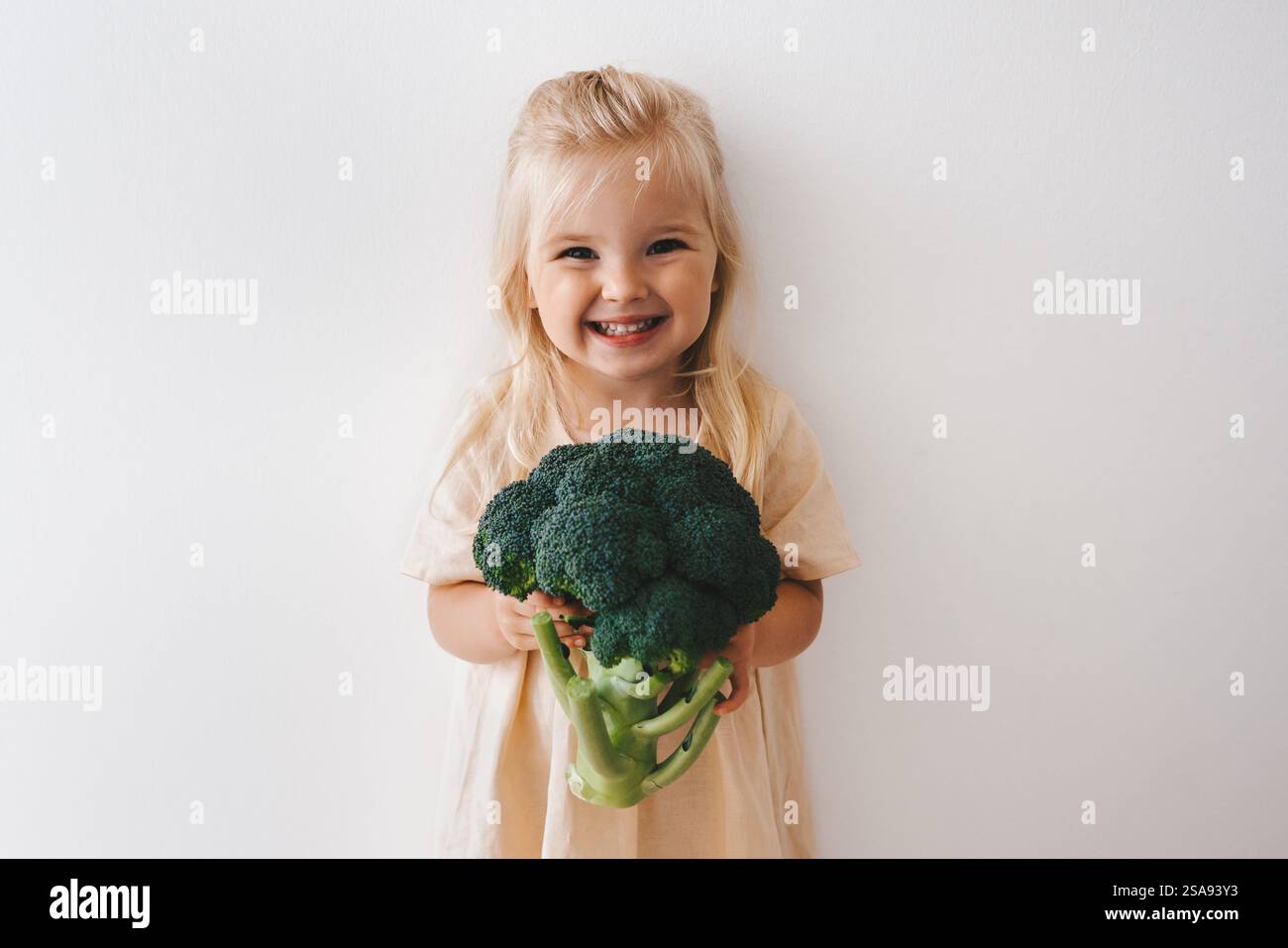 Bambino con broccoli cibo vegano sano verdure organiche raccolto dieta a base di piante nutrizione divertente 3 anni ragazza felice sorridente ragazzo Foto Stock