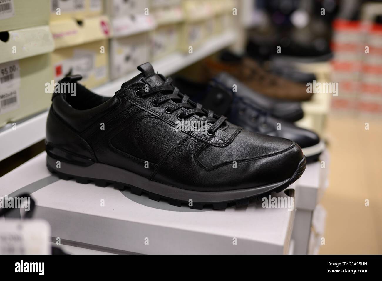 File di scarpe da uomo in un centro commerciale nel reparto di articoli sportivi, scarpe da ginnastica, primo piano. Shopping maschile, commercio, vendita. Foto Stock