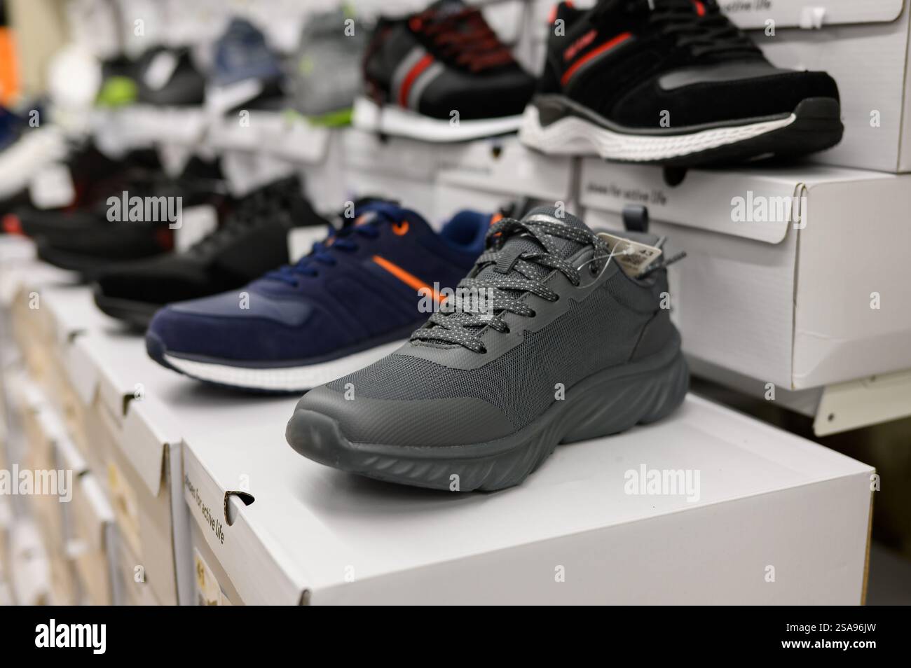 File di scarpe da uomo in un centro commerciale nel reparto di articoli sportivi, scarpe da ginnastica, primo piano. Shopping maschile, commercio, vendita. Foto Stock