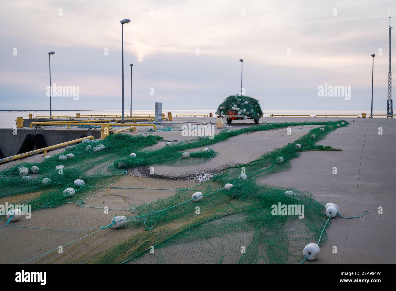 Reti da pesca sulla banchina del porto. Un mucchio di colorate reti da pesca e galleggianti sulla banchina del porto. La sera d'estate in riva al mare. Foto Stock