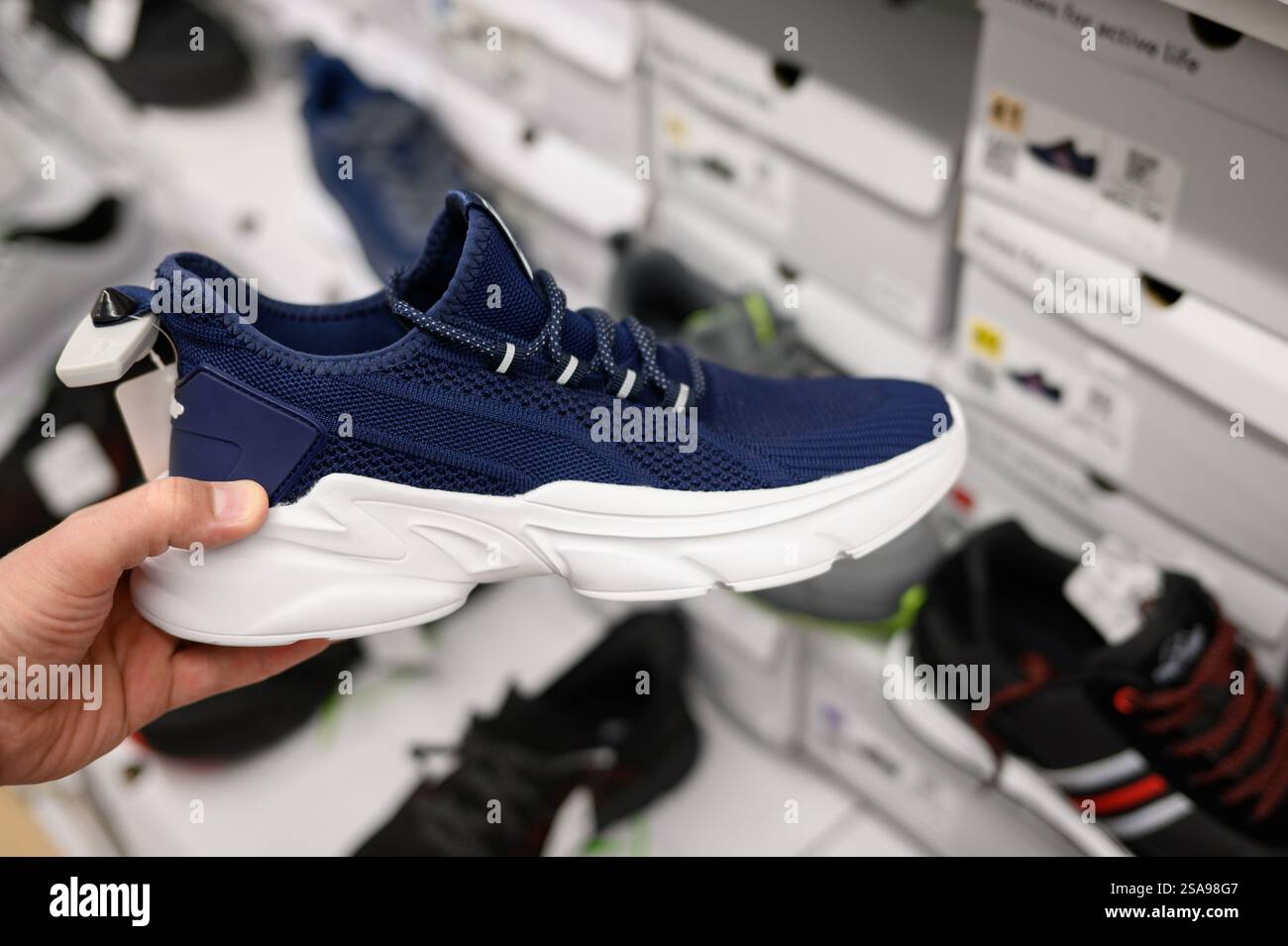 Un uomo sceglie le scarpe in un centro commerciale nel dipartimento di articoli sportivi, da vicino. Concetto di shopping maschile Foto Stock