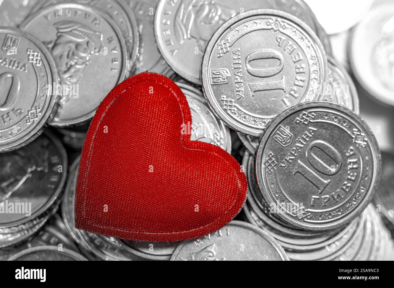 Cuore rosso in mezzo allo sfondo delle monete. Soldi per viaggi, gioielli, piacere o beneficenza. San Valentino Foto Stock