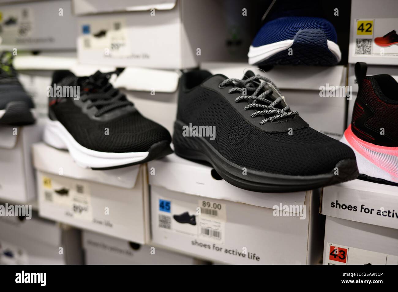 File di scarpe da uomo in un centro commerciale nel reparto di articoli sportivi, scarpe da ginnastica, primo piano. Shopping maschile, commercio, vendita. Foto Stock