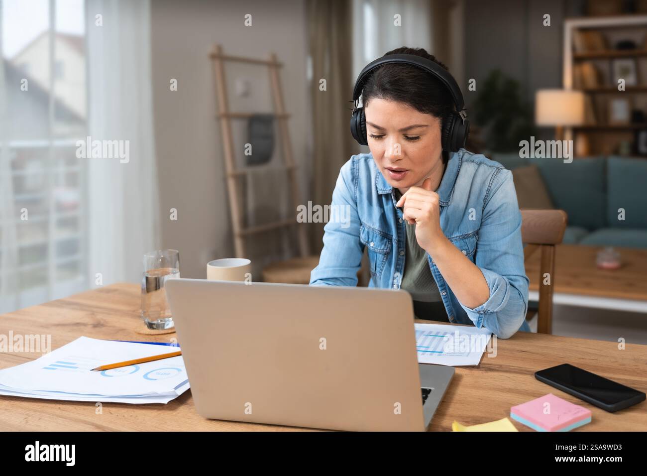 Giovane donna d'affari freelance che partecipa a un corso di formazione online su computer portatile webcam teleconferenza in corso di osservazione e ascolto educatore Foto Stock