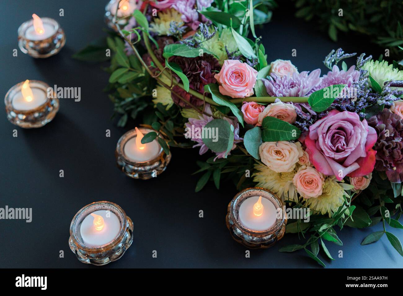Decorazioni per matrimoni con candele e fiori a LED su sfondo nero. Composizione floreale STILL Life Foto Stock