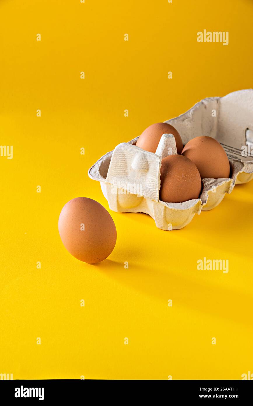 natura morta di un uovo e di un cartone di uova su uno schermo giallo Foto Stock