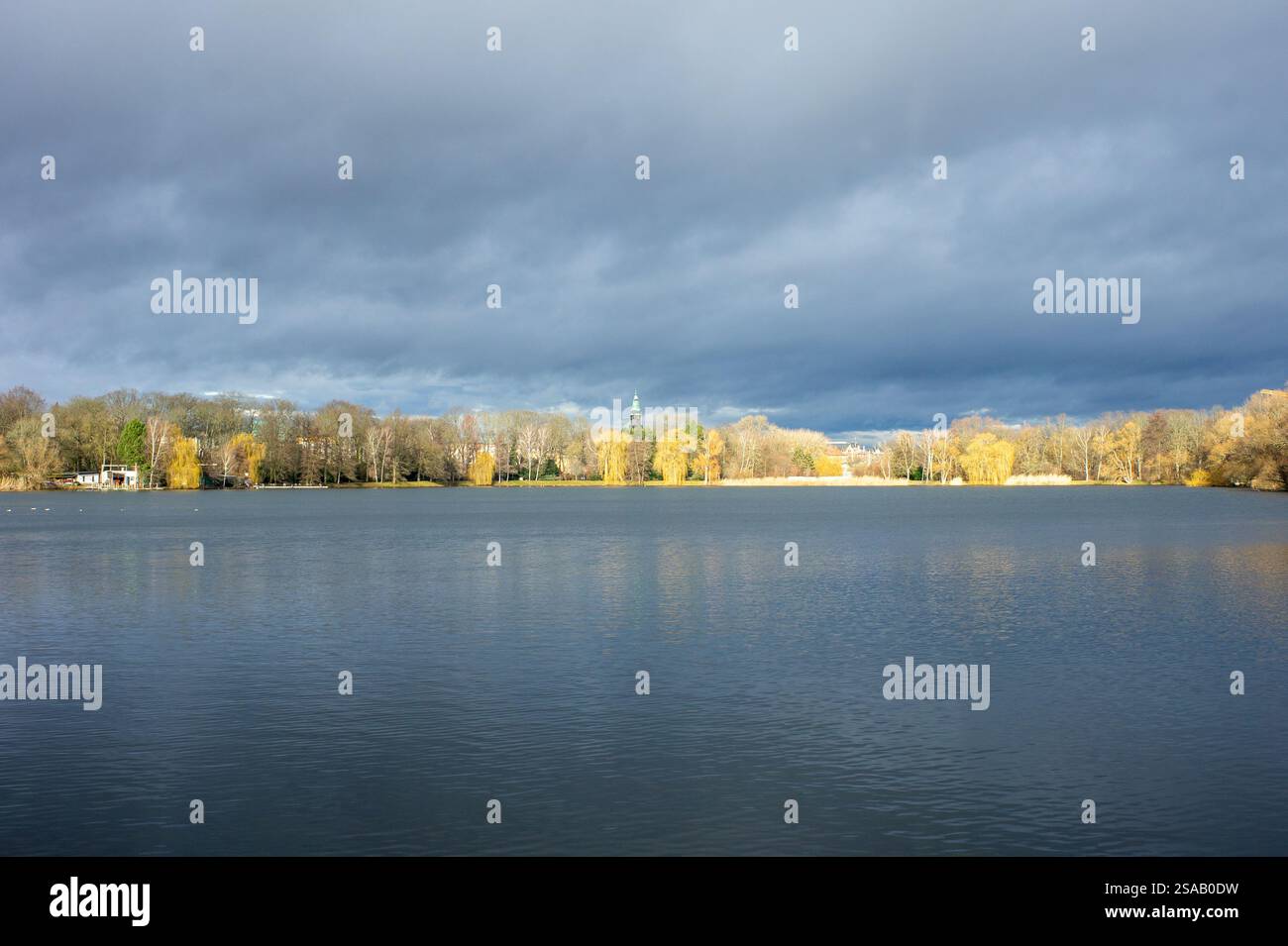 Atmosfera di tempesta sullo Zwickauer Schwanenteich con luce solare tra gli alberi, Sassonia Germania Foto Stock