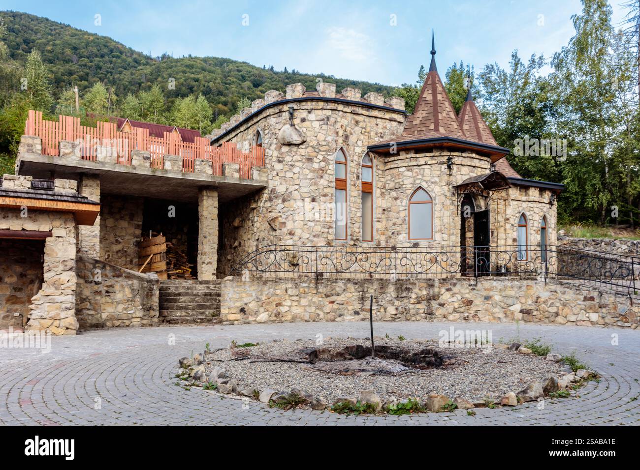 Un edificio simile a un castello con una facciata in pietra e un grande cortile. L'edificio ha un tetto in pietra e un camino in pietra Foto Stock