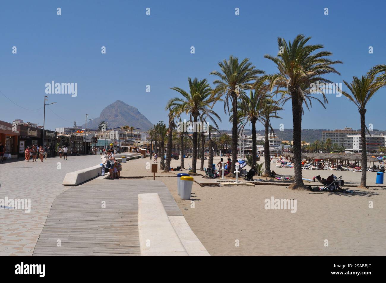 Negozi e ristoranti sulla spiaggia di Arenal con folle estive e Montgo sullo sfondo Foto Stock