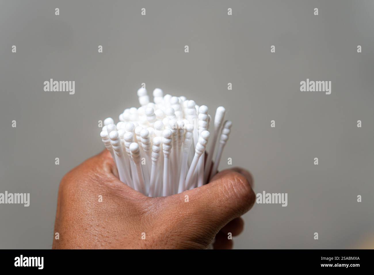 Vista ravvicinata di una pila di bastoncini di cotone bianchi sparsi su un asciugamano scuro, con un panno morbido sullo sfondo. Foto Stock