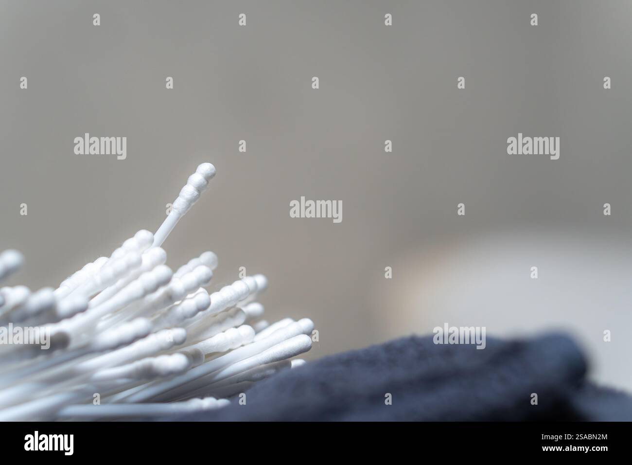 Primo piano di bastoncini di cotone impilati su una superficie morbida, con sfondo sfocato. L'immagine cattura la consistenza e i dettagli dei tamponi, enfasi Foto Stock