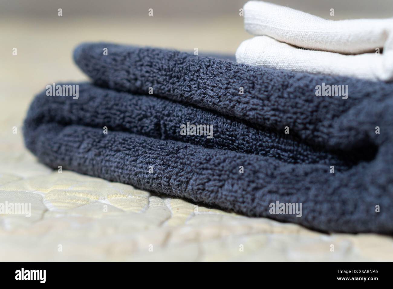 Primo piano di asciugamani scuri e chiari piegati con cura su una superficie ruvida, che mostrano il loro tessuto morbido e colori contrastanti. Foto Stock