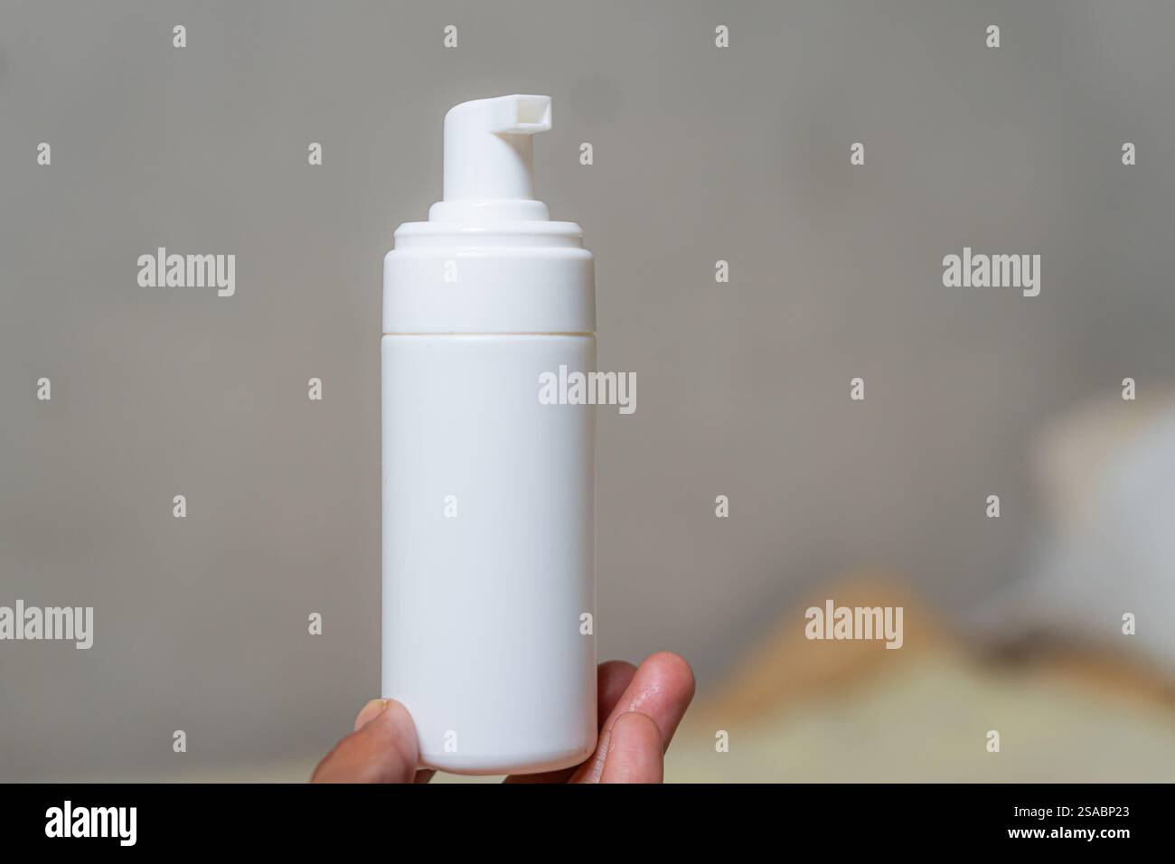 Una persona che tiene in mano un biberon bianco su uno sfondo sfocato, mostrando il design e la semplicità del prodotto. Foto Stock