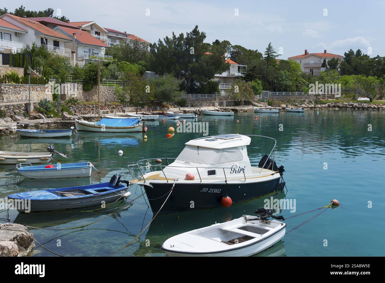 Piccole imbarcazioni che galleggiano in acque calme vicino a case costiere e vegetazione lussureggiante, porto, Starigrad, Starigrad-Paklenica, Zara, Croazia, Europa Foto Stock