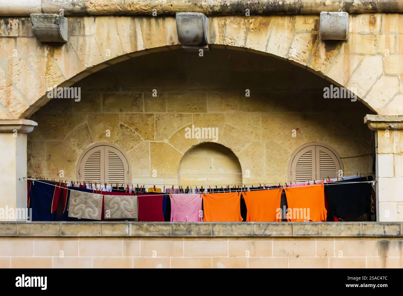 Vestiti che si asciugano all'esterno su un balcone sotto un arco di pietra Foto Stock