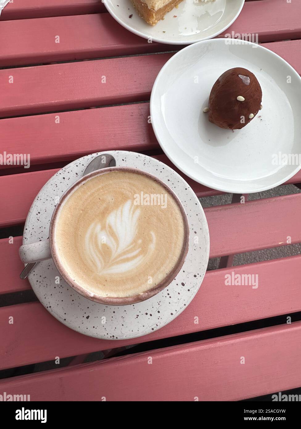 Vista dall'alto della tazza da caffè con cappuccino o latte e dessert al cioccolato nelle vicinanze, sfondo in legno rosa. Caffetteria, concetto di caffetteria Foto Stock