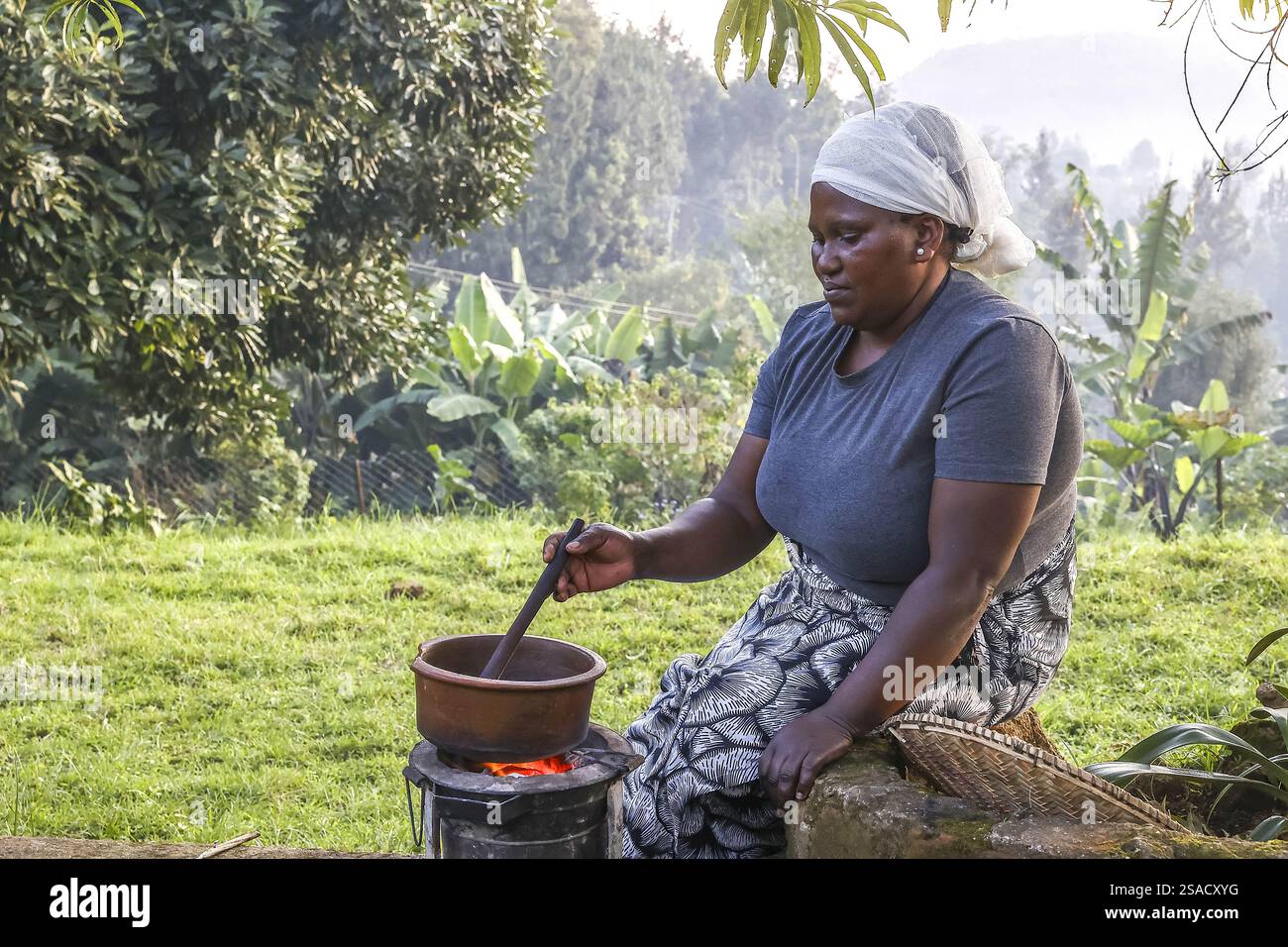 Donna che tosta chicchi di caffè nel villaggio di N’giresi, Tanzania Foto Stock