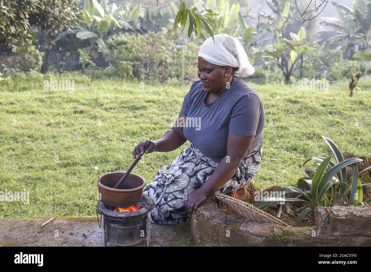 Donna che tosta chicchi di caffè nel villaggio di N’giresi, Tanzania Foto Stock