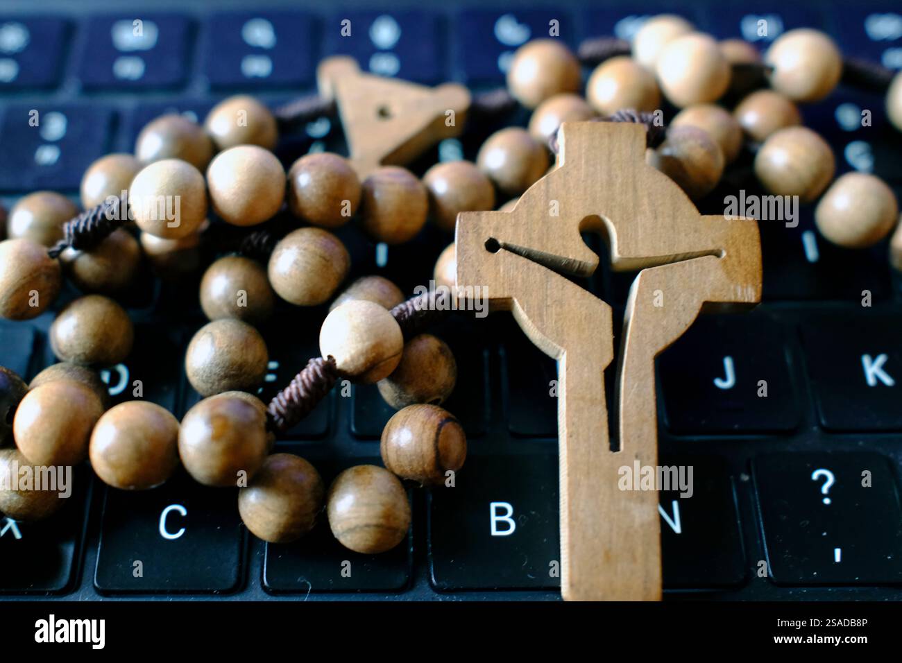 Tastiera per computer con rosario di legno. Foto Stock