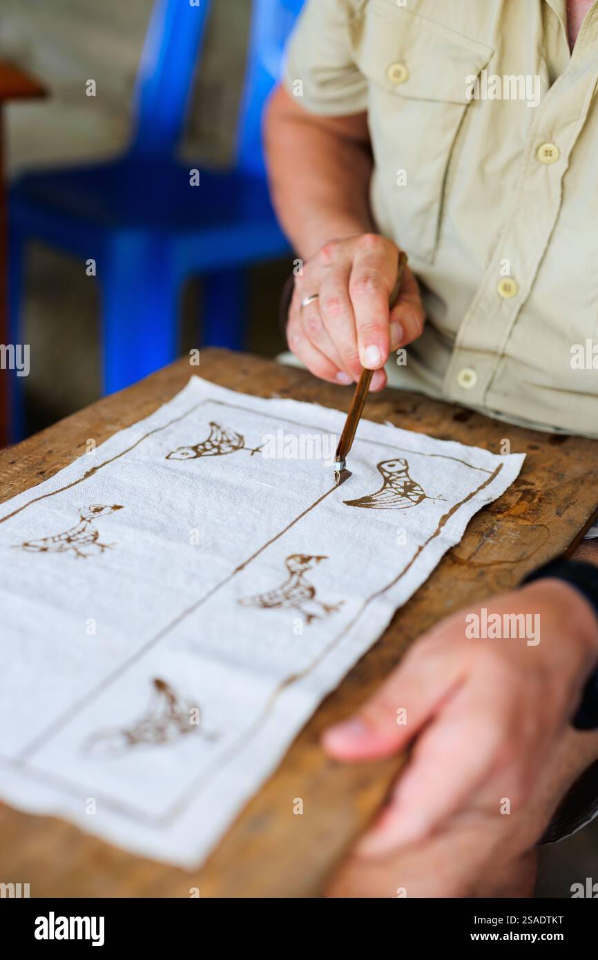 Uomo caucasico che crea batik disegnando con cera calda Foto Stock