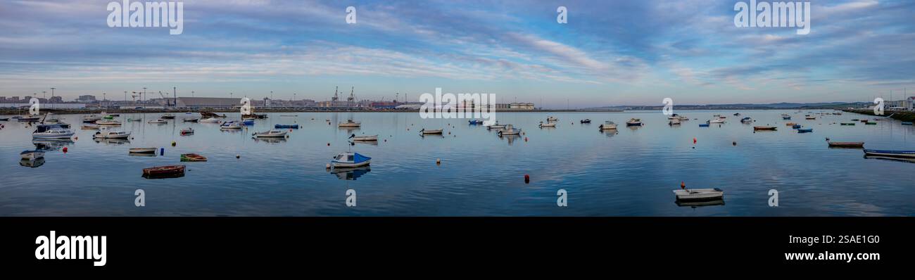 I relitti arrugginiti si arenano nella baia di Santander Cantabria, in Spagna, con piccole barche da pesca e yacht a motore ormeggiati alle boe nel pomeriggio invernale Foto Stock