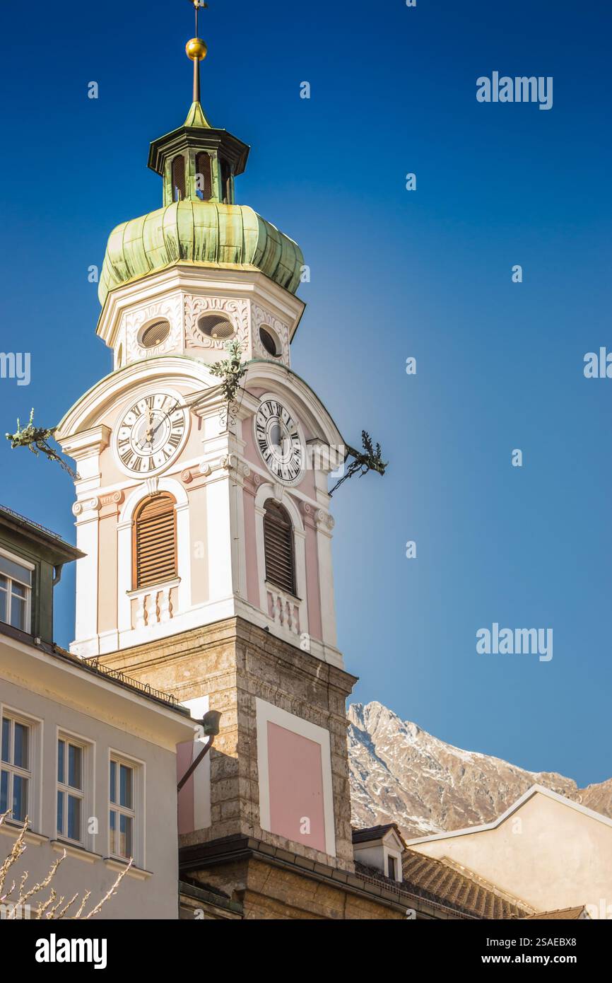 Torre dell'orologio nel municipio di Innsbruck, Austria. Punto di riferimento di Innsbruck nella giornata di sole in inverno. Antica chiesa e montagne alpine sullo sfondo, Innsbruck. Foto Stock