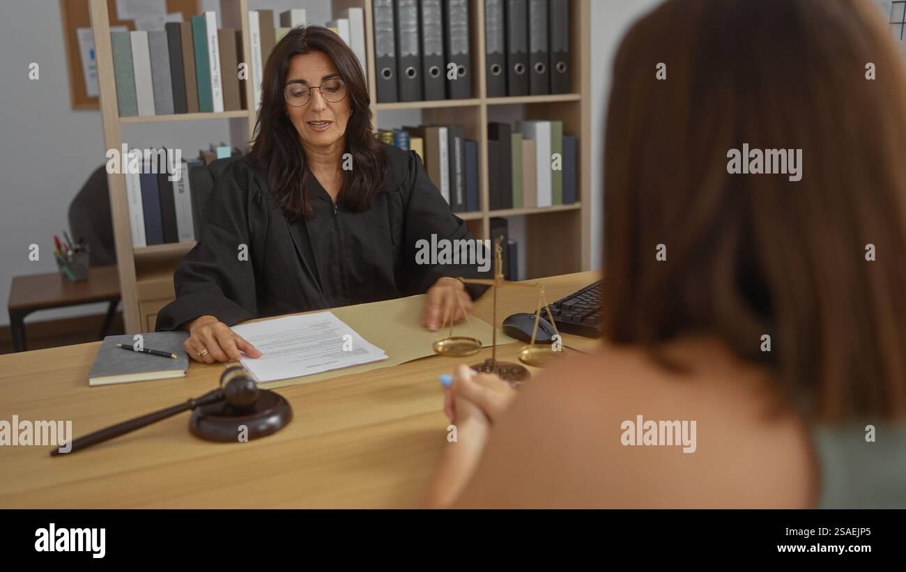 Donna giudice in carica che discute con il cliente in ambito legale professionale mostrando documenti Foto Stock