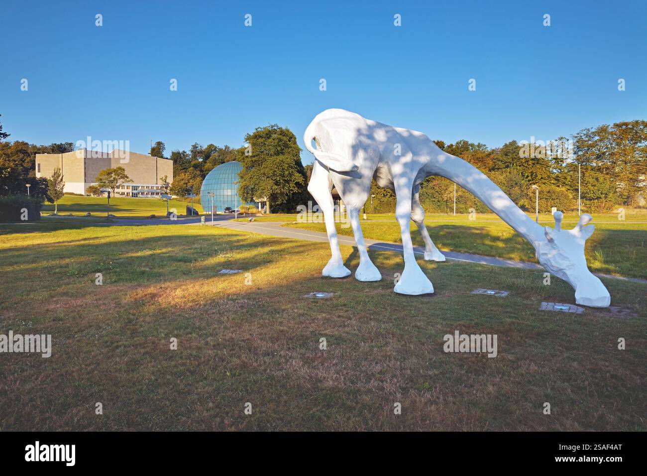 Scultura di giraffa bianca sulla testa meridionale con il Teatro Scharoun Wolfsburg e il planetario sullo sfondo, Germania, bassa Sassonia, Wolfsburg Foto Stock