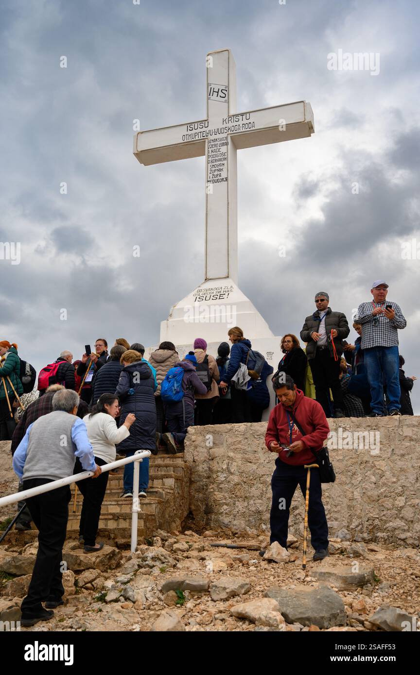 Pellegrini intorno alla croce bianca sulla cima del monte Križevac (la montagna della Croce) a Medjugorje. Foto Stock