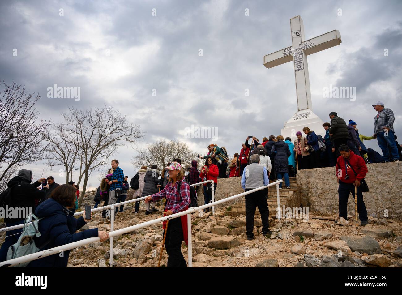 Pellegrini intorno alla croce bianca sulla cima del monte Križevac (la montagna della Croce) a Medjugorje. Foto Stock