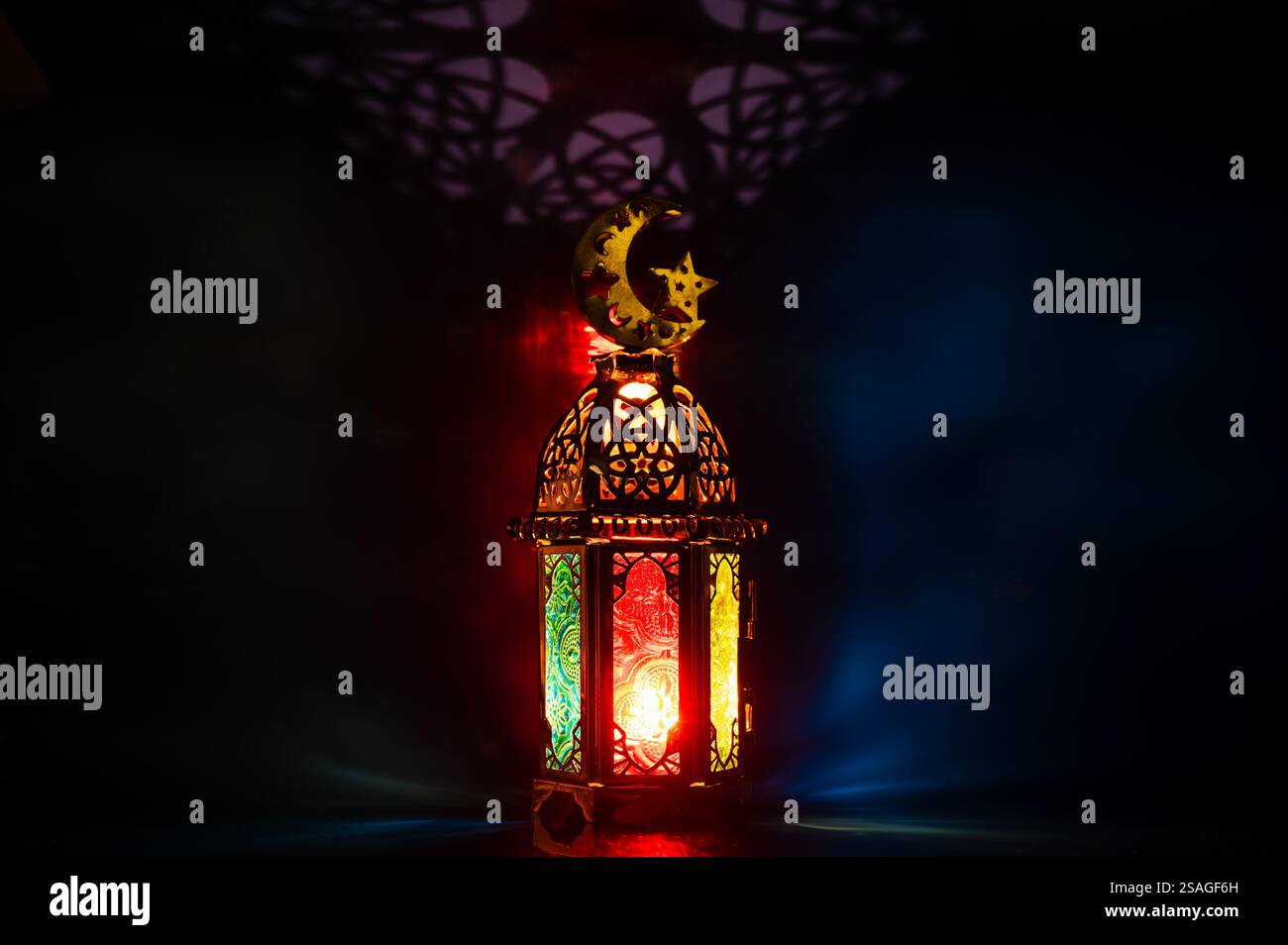 Lanterna con il simbolo della luna sulla parte superiore con sfondo di ombra luminosa colorata per la festa musulmana del mese santo di Ramadan Kareem. Foto Stock