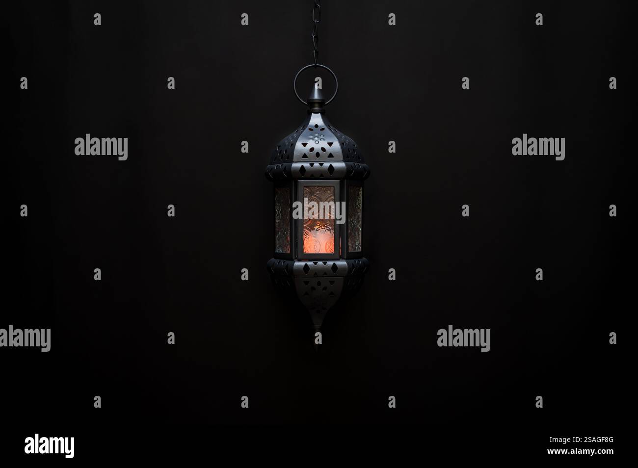 Lanterna nera appesa con luce su sfondo scuro per la festa musulmana del mese santo del Ramadan Kareem. Foto Stock