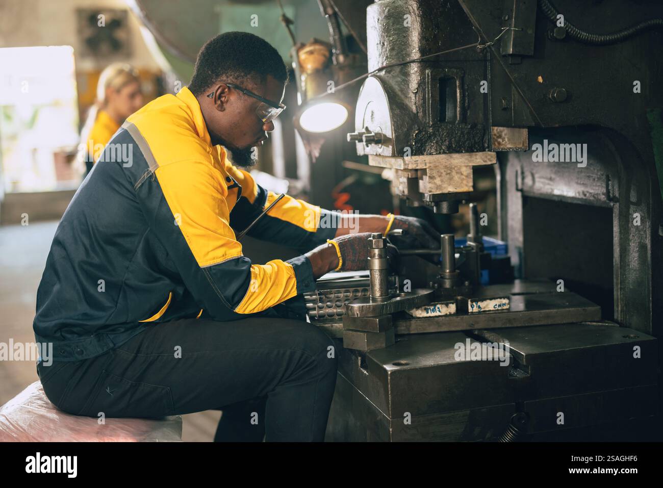 lavoratore nero africano che lavora nell'industria dei metalli pesanti fabbrica di punzonatura stampaggio macchina dell'acciaio Foto Stock