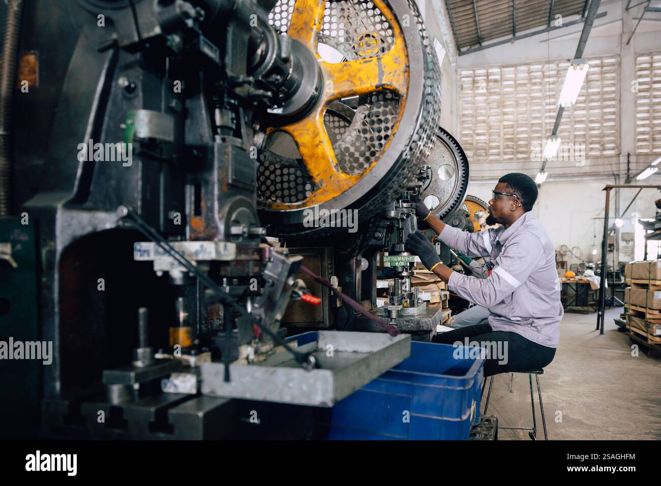 lavoratore nero africano che lavora nell'industria dei metalli pesanti fabbrica di punzonatura stampaggio macchina dell'acciaio Foto Stock