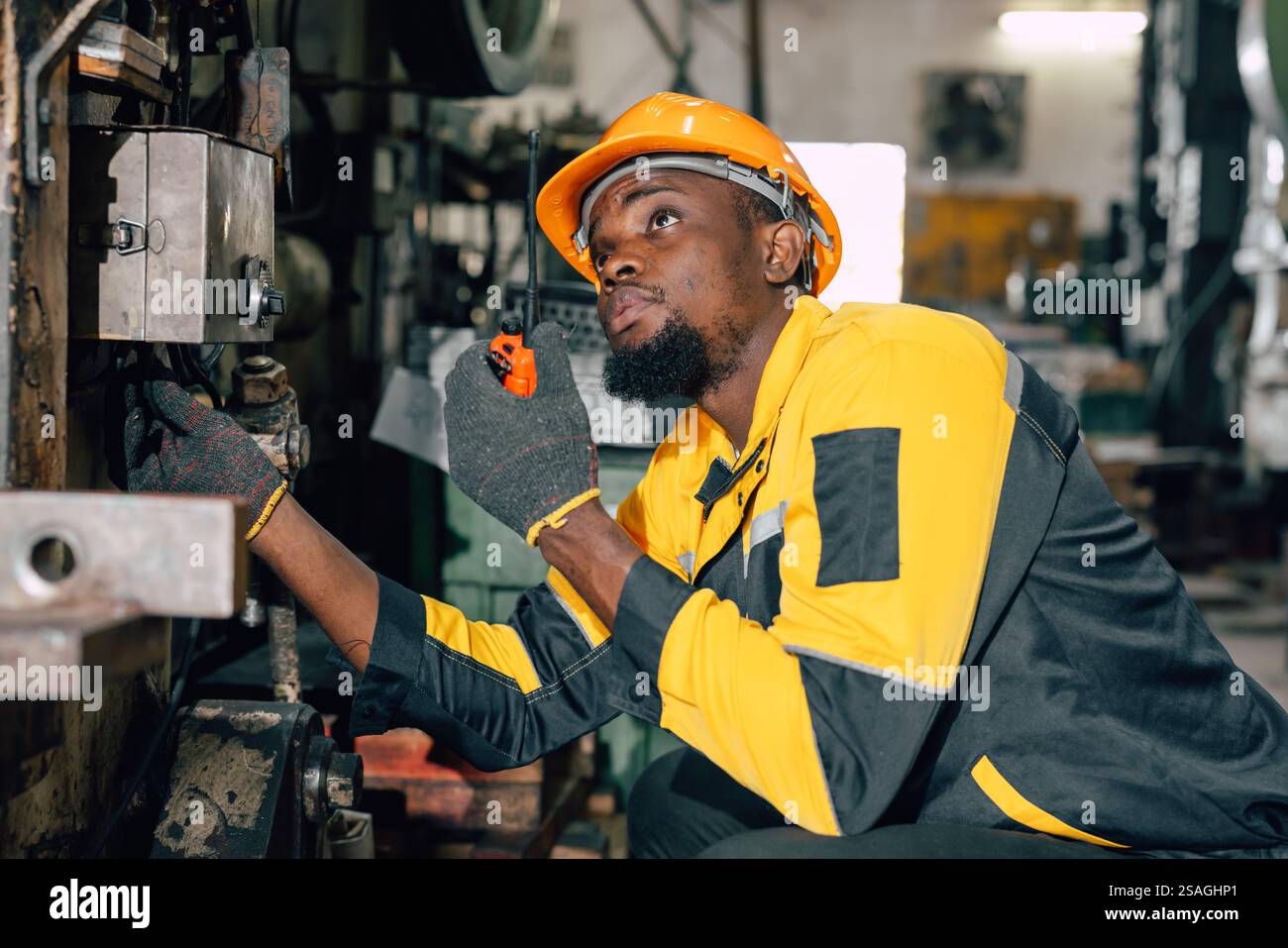 squadra di ingegneri africani neri professionali che ispezionano la macchina di servizio nella fabbrica dell'industria pesante Foto Stock