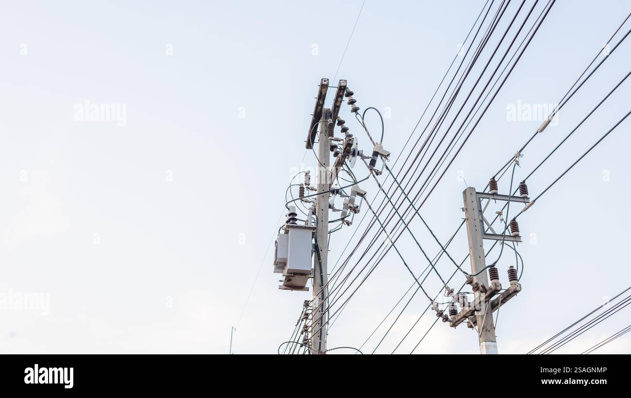Distribuzione del trasferimento di energia elettrica su palo in calcestruzzo su sfondo bianco del cielo, trasformatore di potenza ad alta tensione CA, Un colpo ad angolo basso di una potenza Foto Stock