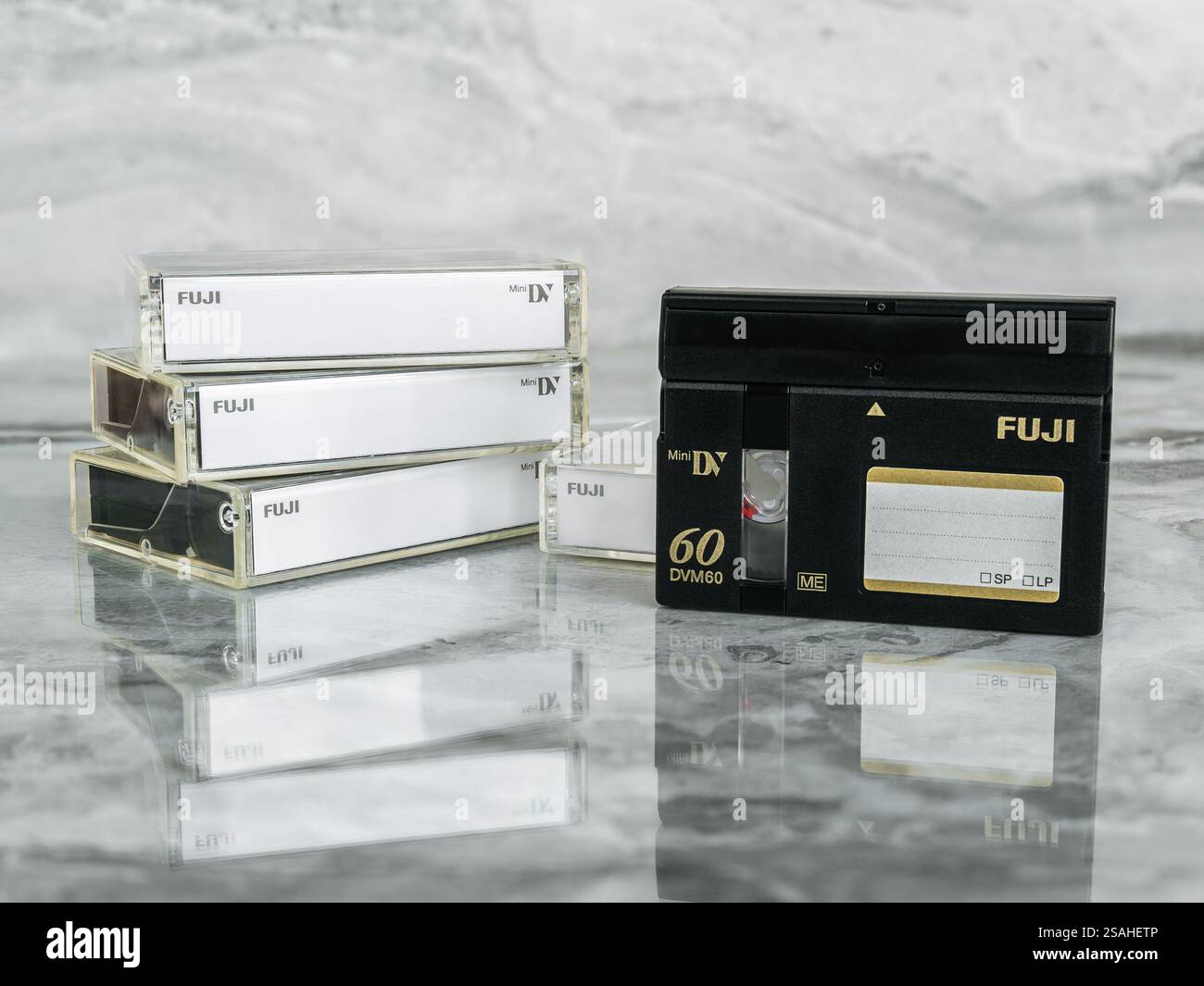 Quattro videocassette digitali Mini DV Fuji DVM60CME e DVCasstte su un ripiano in marmo grigio lucido con riflesso Foto Stock