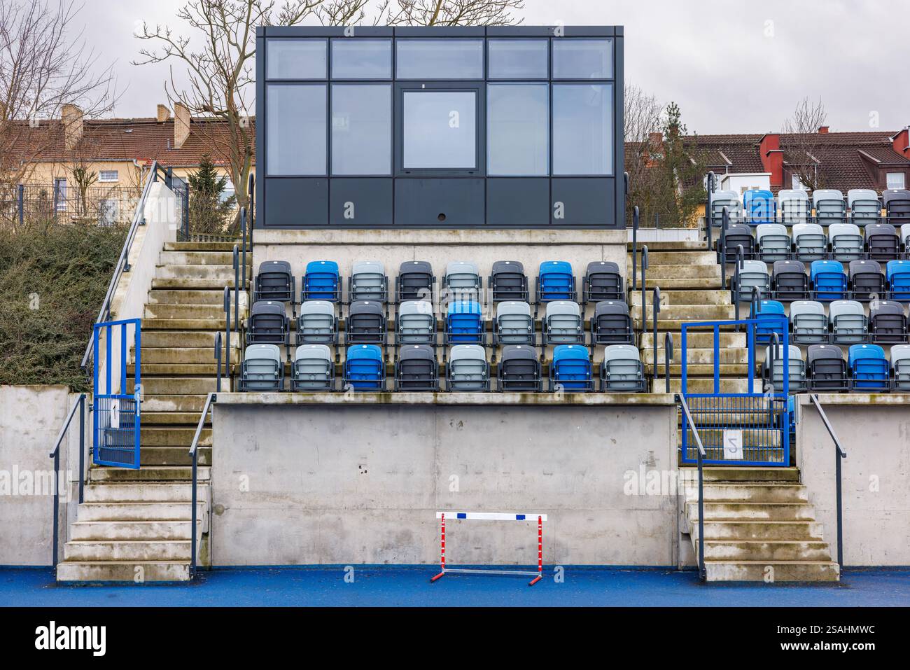 Sedili pieghevoli blu e grigi presso lo stadio cittadino. Stand del commentatore di vetro. Scale di cemento che portano alle tribune. Foto Stock