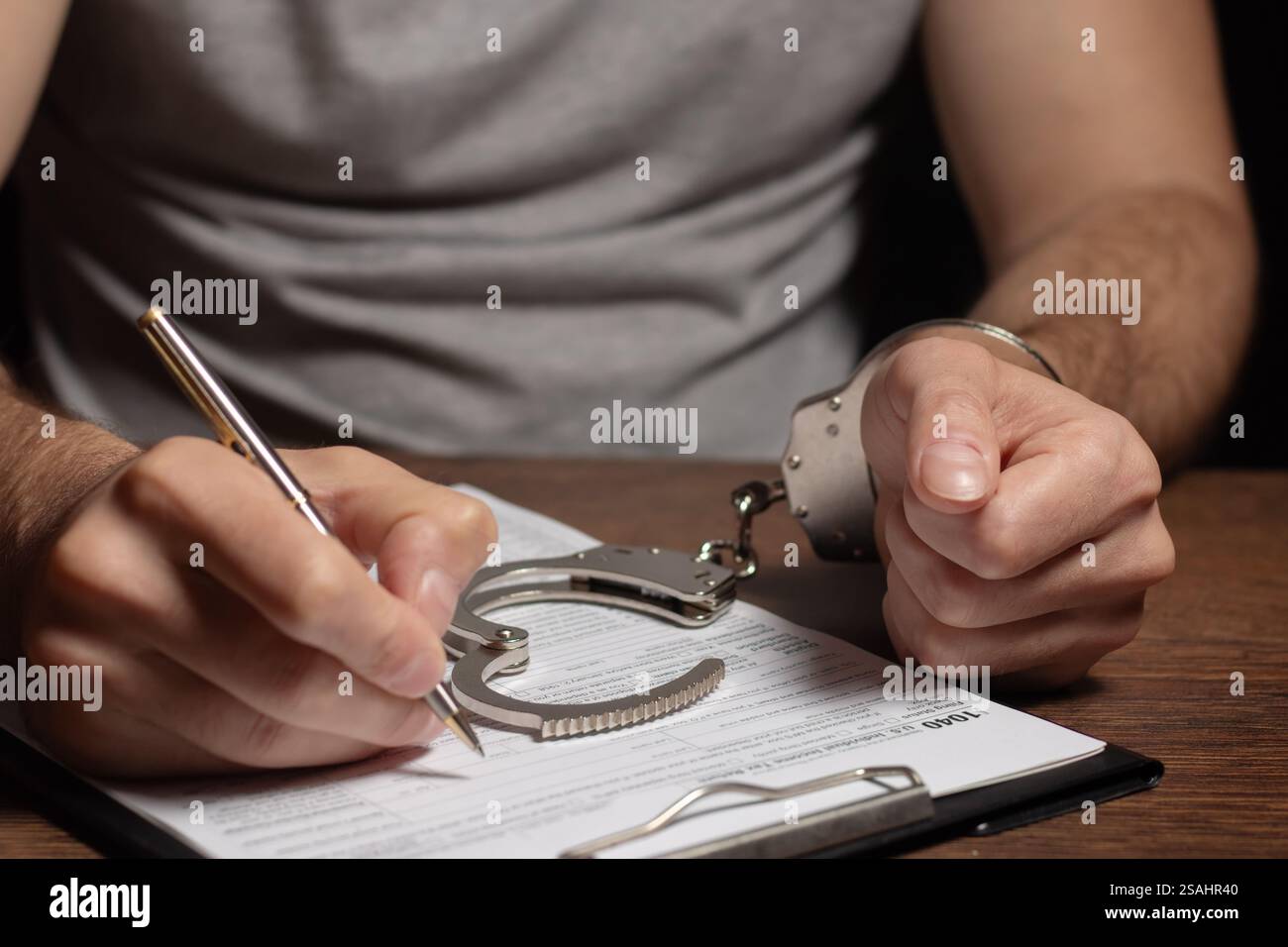 Evasione fiscale, criminalità e frode. Uomo in manette che compila il modulo delle imposte documenti di dichiarazione dei redditi e manette Foto Stock