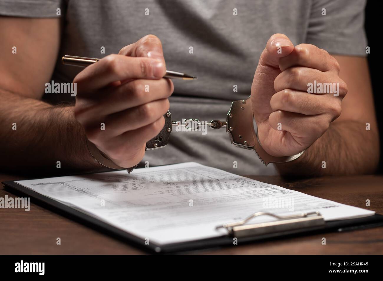 Evasione fiscale, criminalità e frode. Uomo in manette che compila il modulo delle imposte documenti di dichiarazione dei redditi e manette Foto Stock