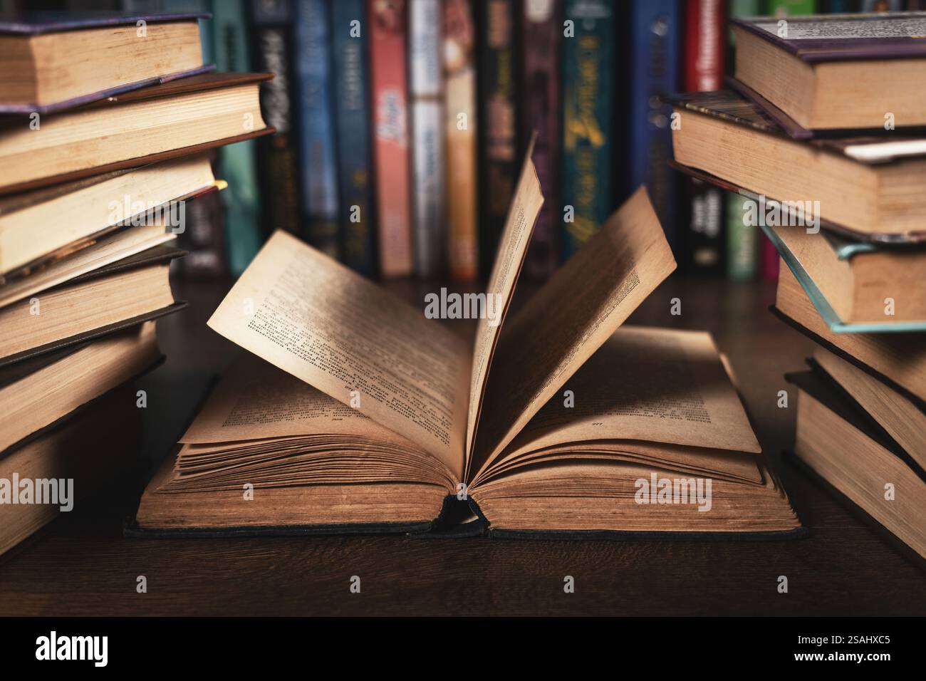 Istruzione il concetto di apprendimento con apertura del libro o dei libri di testo nella vecchia libreria, pila pile di letteratura accademica di testo archivio sul banco di lettura e di corsia Foto Stock