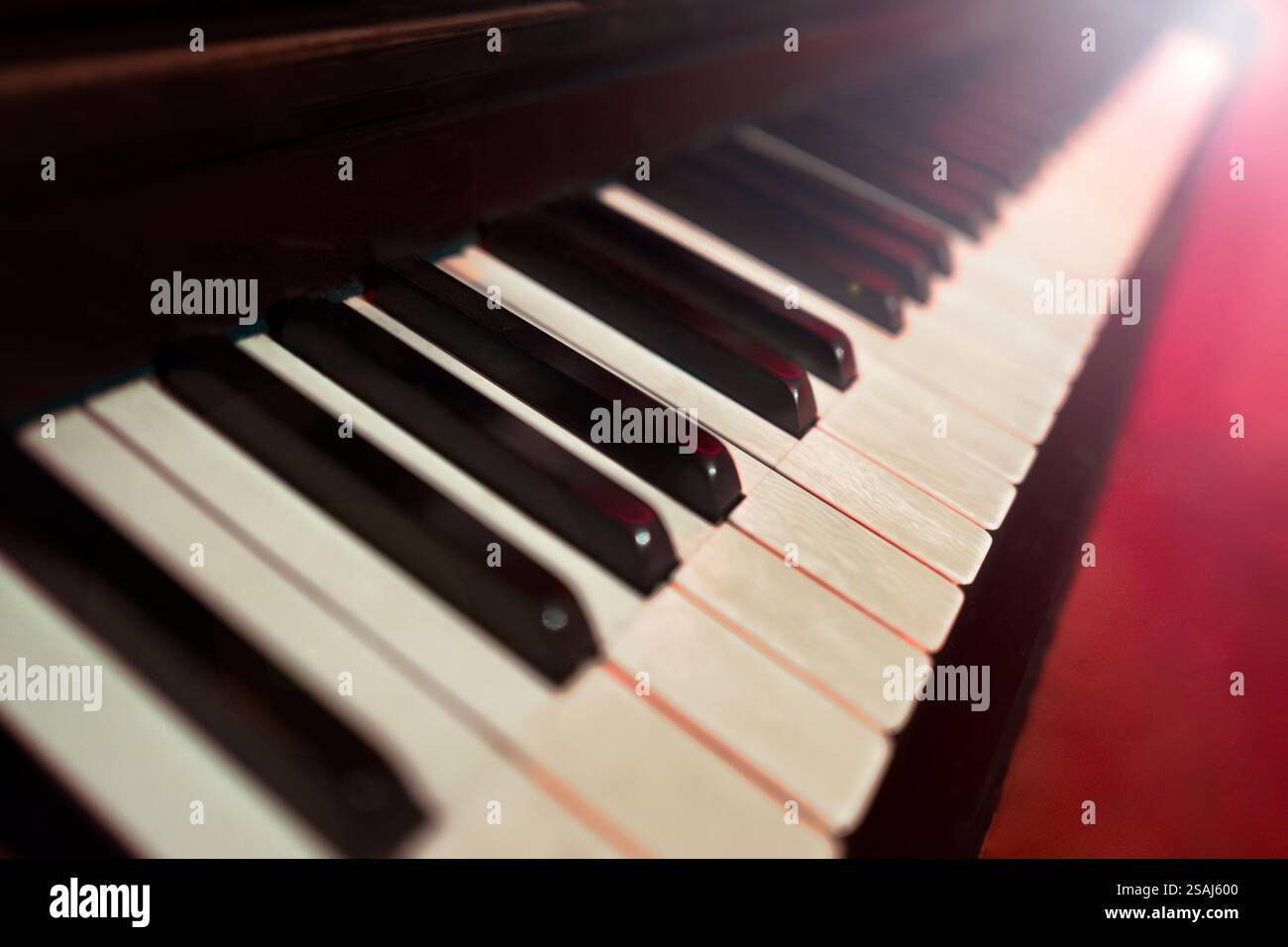 Messa a fuoco superficiale con vista ravvicinata della tastiera a pianoforte vintage in un'atmosfera suggestiva con luce rossa Foto Stock