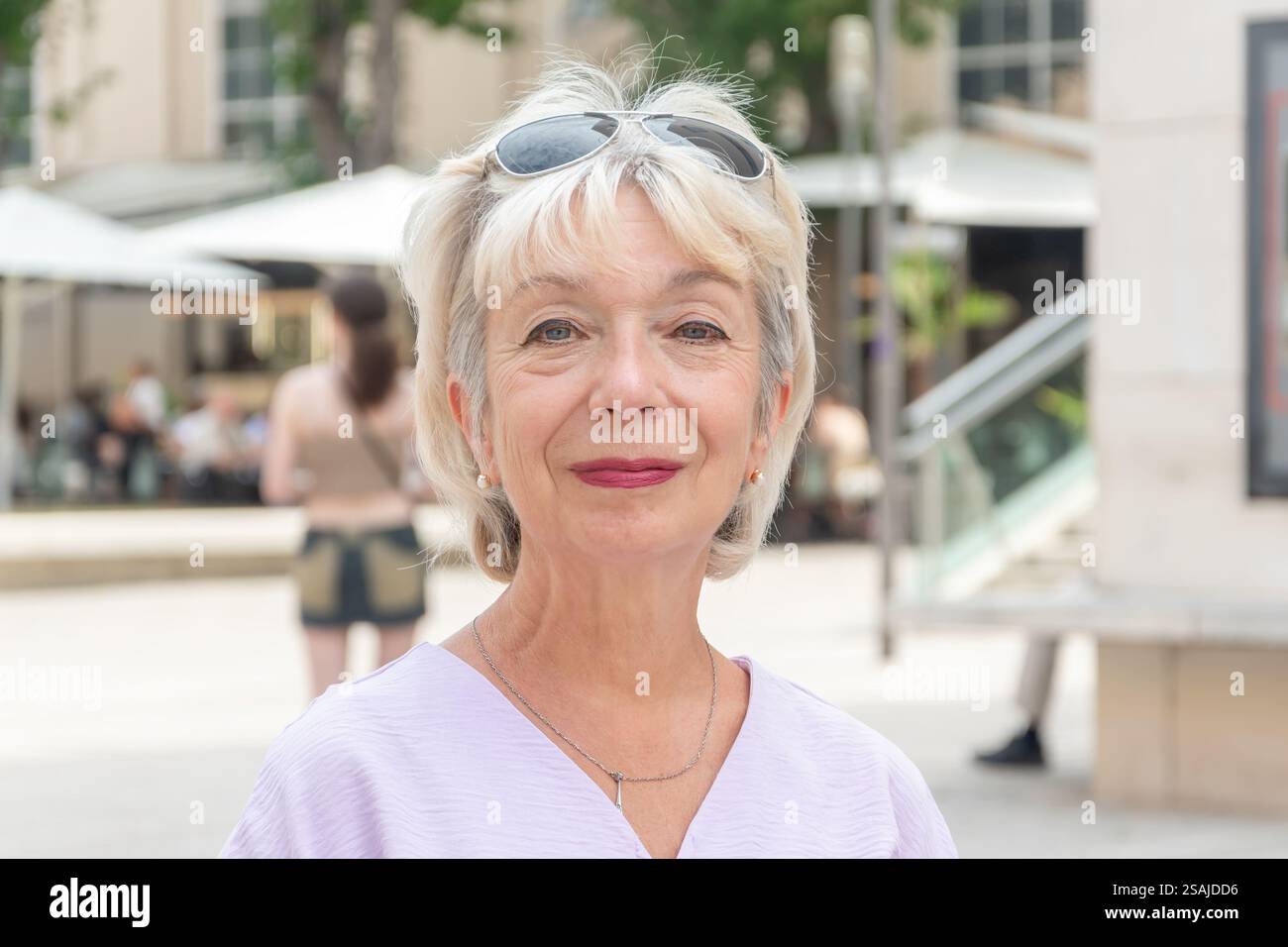 Ritratto di strada di una donna anziana di 70-75 anni su uno sfondo sfocato di una città europea Foto Stock