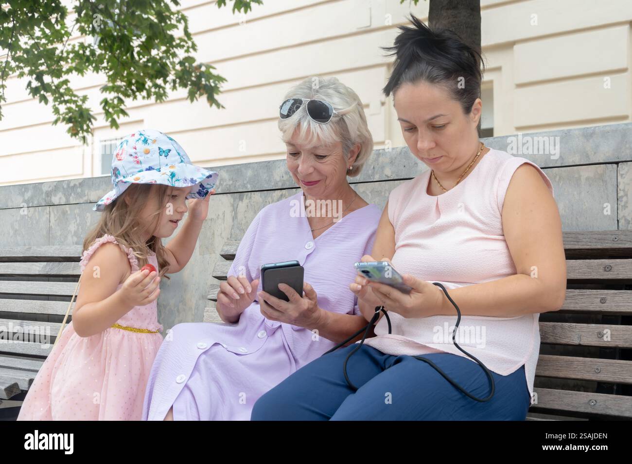 Nonna, mamma e nipote in giro, interagendo tra loro e con i loro telefoni. Foto Stock