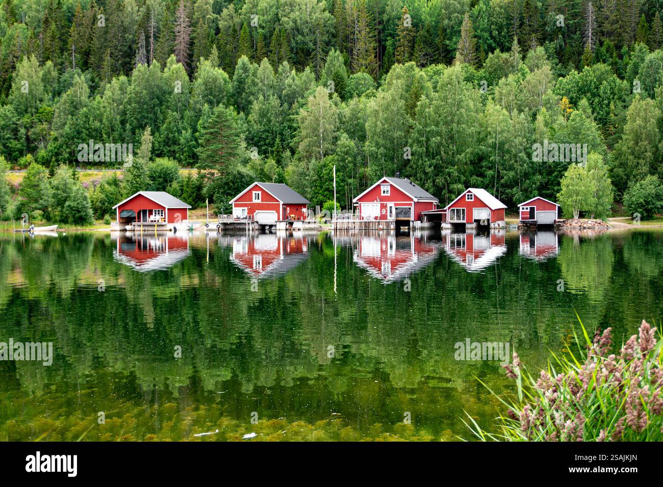 Case rosse al tramonto su un lago, Höga Kusten, Svezia Foto Stock